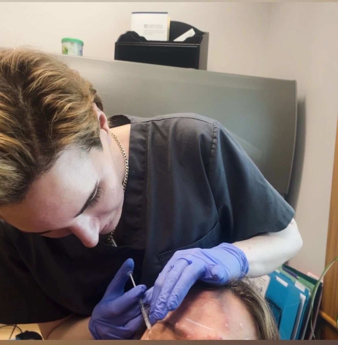 Injector Tanner administering injection on patient's forehead.